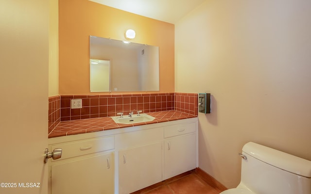 bathroom featuring toilet, tile patterned flooring, backsplash, and vanity