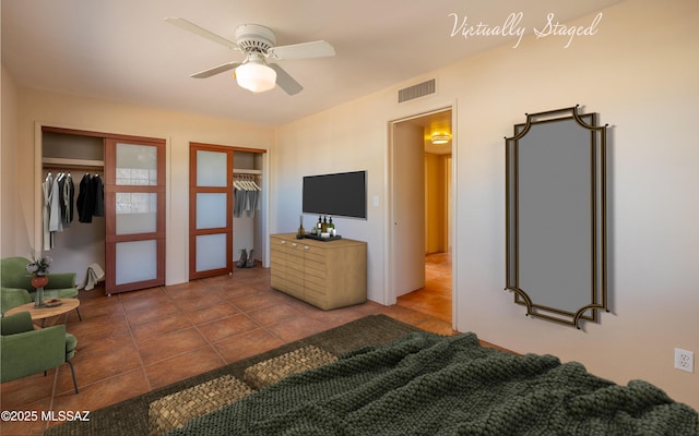 tiled bedroom with a ceiling fan, visible vents, and two closets