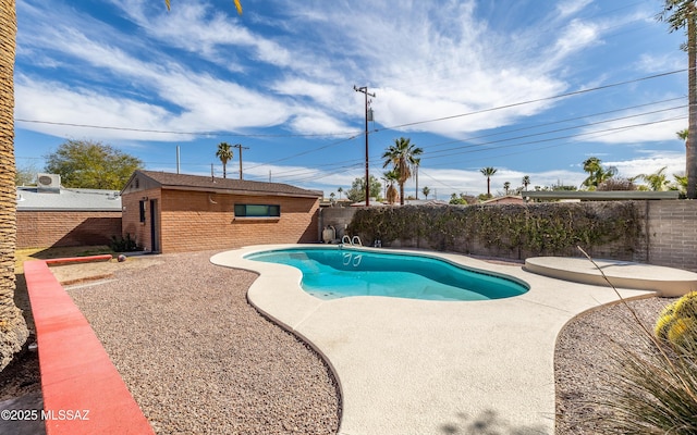 view of swimming pool featuring a fenced in pool, an outbuilding, a patio area, and a fenced backyard