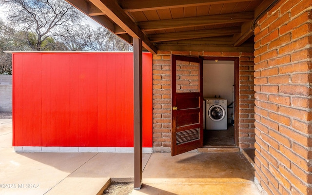 view of exterior entry with washer / clothes dryer and brick siding