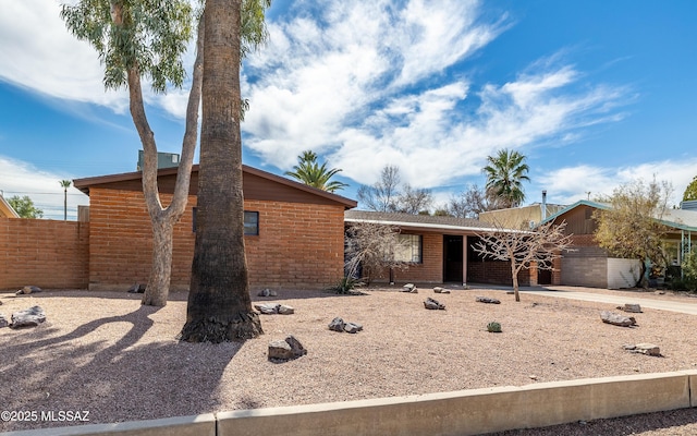 mid-century inspired home with a garage, brick siding, and fence