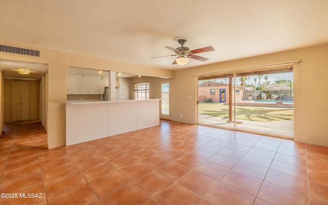 interior space featuring light tile patterned floors, a ceiling fan, visible vents, and a wealth of natural light