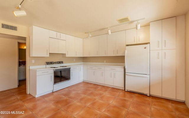 kitchen featuring rail lighting, white appliances, light countertops, and visible vents