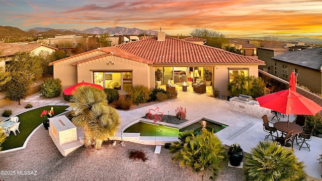 back of house featuring a patio, a tiled roof, area for grilling, and stucco siding