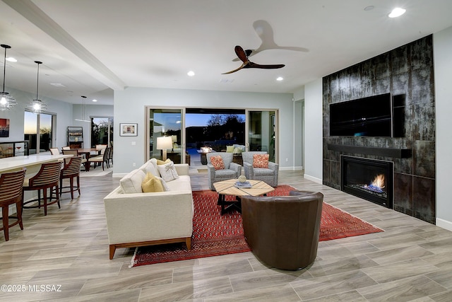 living area with a tile fireplace, ceiling fan, baseboards, and recessed lighting