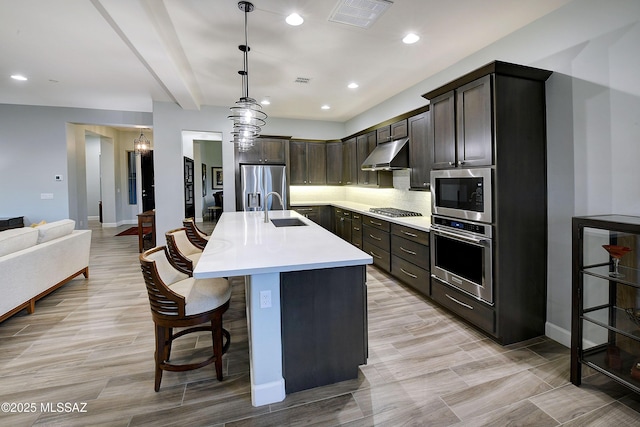 kitchen featuring under cabinet range hood, stainless steel appliances, a sink, visible vents, and light countertops