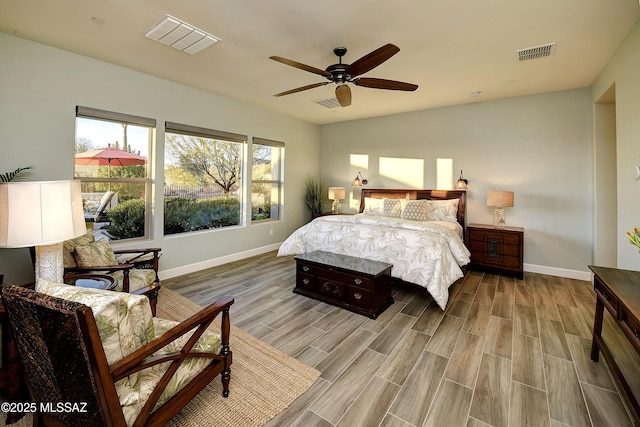 bedroom with a ceiling fan, visible vents, baseboards, and wood finished floors