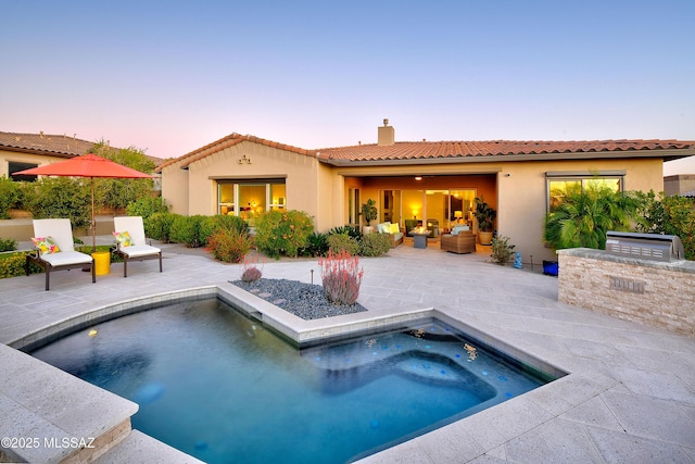 back of property with a patio area, a chimney, exterior kitchen, and stucco siding