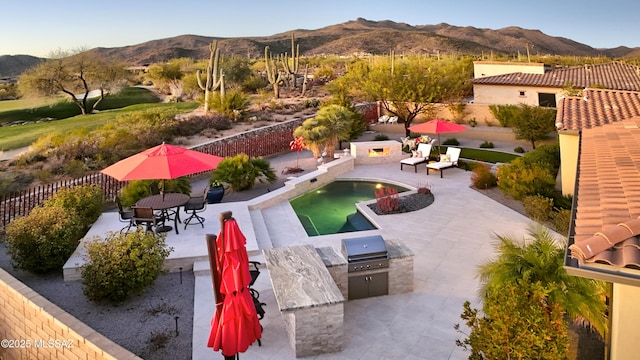 view of swimming pool featuring a patio, a fenced backyard, a mountain view, area for grilling, and exterior kitchen