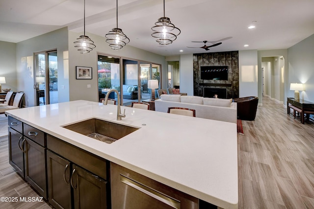 kitchen featuring open floor plan, light countertops, a sink, and light wood-style flooring