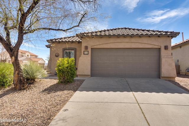 mediterranean / spanish-style home with a garage, driveway, a tiled roof, and stucco siding