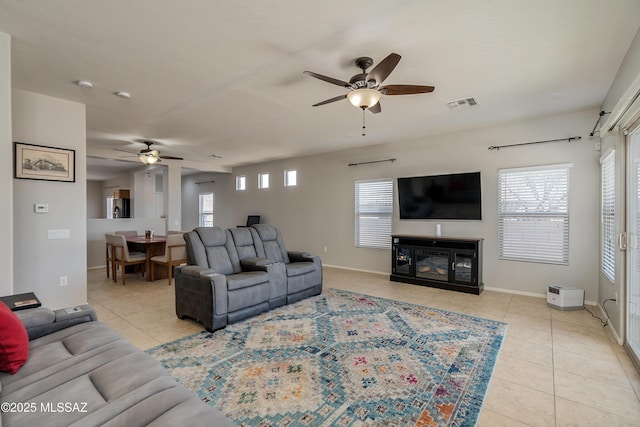 living room with light tile patterned flooring, a glass covered fireplace, visible vents, and a healthy amount of sunlight