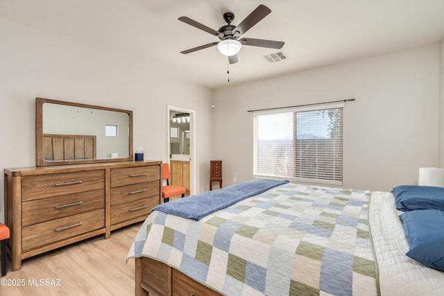 bedroom featuring light wood-style floors, visible vents, ensuite bath, and a ceiling fan