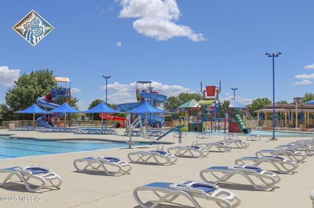 view of pool featuring a water play area, playground community, a water slide, and fence
