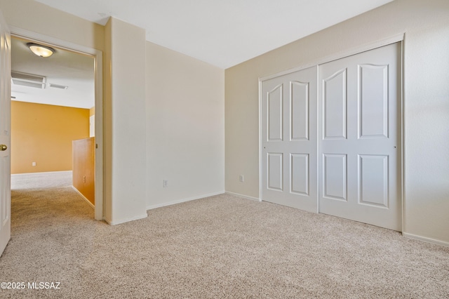 unfurnished bedroom with a closet, light colored carpet, and baseboards