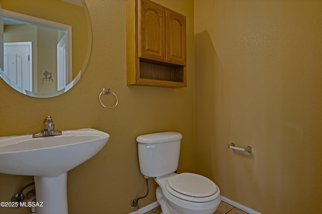 bathroom featuring a sink, tile patterned flooring, toilet, and baseboards