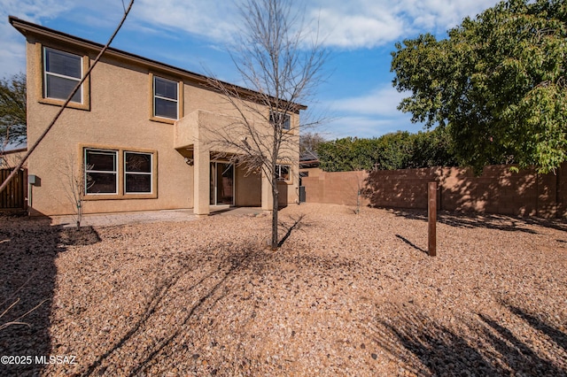 back of house with a fenced backyard and stucco siding