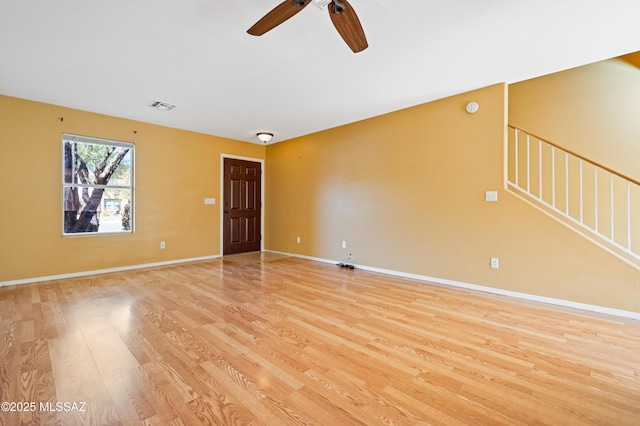 unfurnished room featuring ceiling fan, visible vents, baseboards, light wood-style floors, and stairway