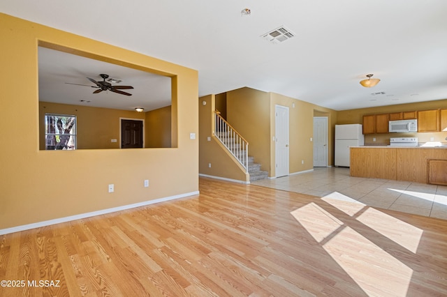 unfurnished living room featuring light wood-style floors, stairs, and visible vents