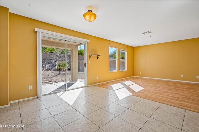 spare room featuring baseboards, visible vents, and light tile patterned flooring