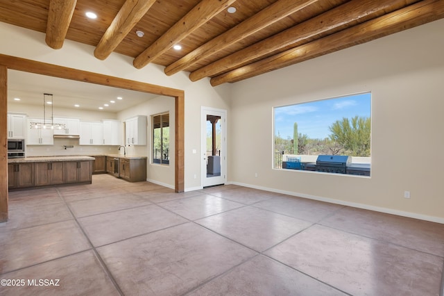 unfurnished living room featuring wooden ceiling, recessed lighting, a sink, baseboards, and beam ceiling