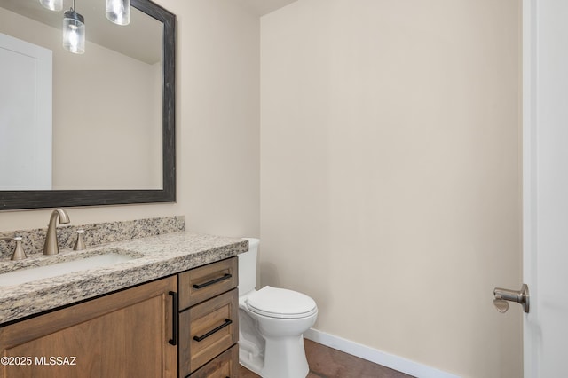 bathroom with vanity, toilet, and baseboards