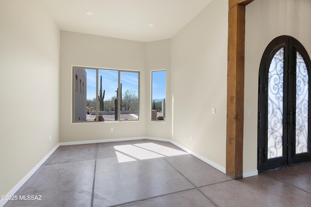 foyer entrance featuring arched walkways, french doors, finished concrete flooring, and baseboards