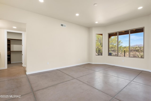 spare room with baseboards, concrete floors, visible vents, and recessed lighting