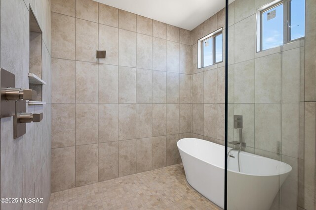 bathroom with tiled shower, a freestanding bath, and tile walls