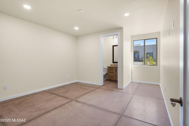 interior space with concrete flooring, recessed lighting, ensuite bath, and baseboards