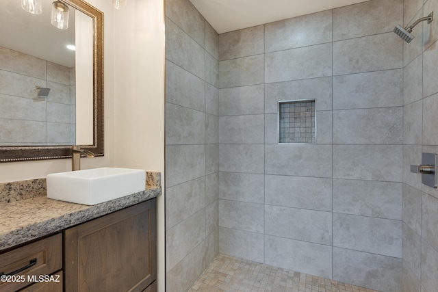 bathroom with a tile shower and vanity