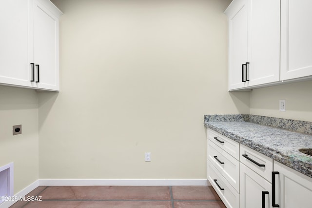 washroom featuring cabinet space, baseboards, electric dryer hookup, and tile patterned floors