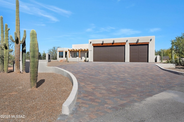 pueblo-style home featuring a garage, decorative driveway, and stucco siding