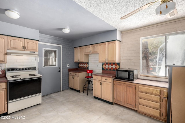 kitchen with light brown cabinets, under cabinet range hood, electric range oven, black microwave, and ceiling fan