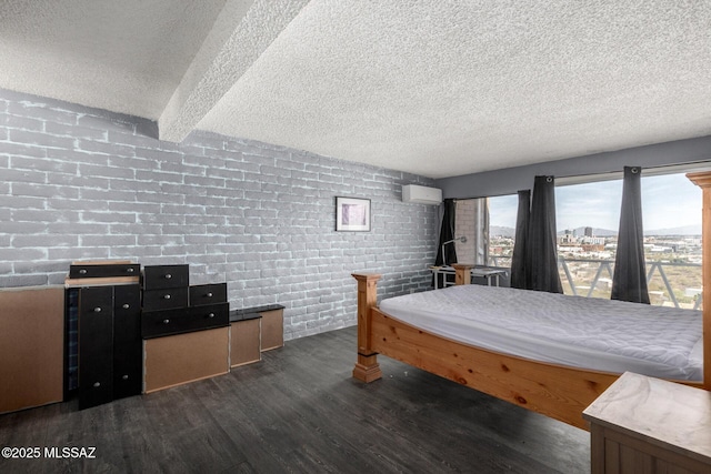 bedroom with a wall mounted air conditioner, dark wood-type flooring, brick wall, and a textured ceiling