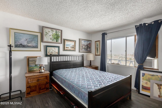 bedroom with cooling unit, a textured ceiling, and wood finished floors