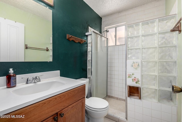 full bathroom featuring a textured ceiling, a stall shower, vanity, and toilet