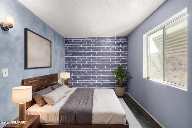 bedroom featuring baseboards, a textured ceiling, and wood finished floors