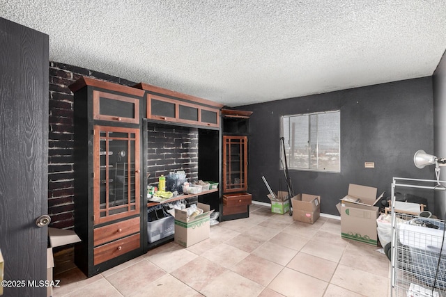 interior space with light tile patterned flooring, a textured ceiling, and baseboards