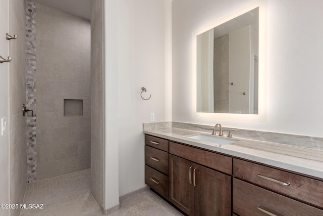 bathroom featuring tiled shower and vanity