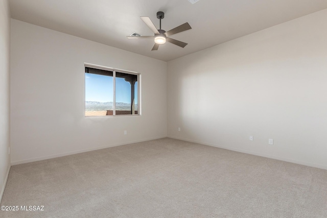 empty room with light carpet, a ceiling fan, and baseboards