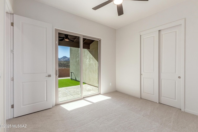 unfurnished bedroom featuring access to outside, carpet flooring, and a ceiling fan