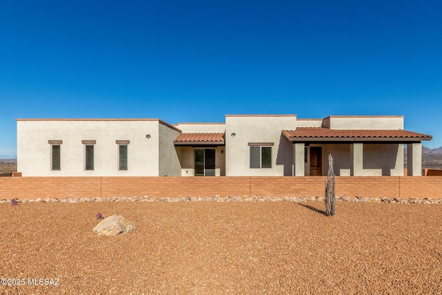 pueblo-style house with a tile roof and stucco siding