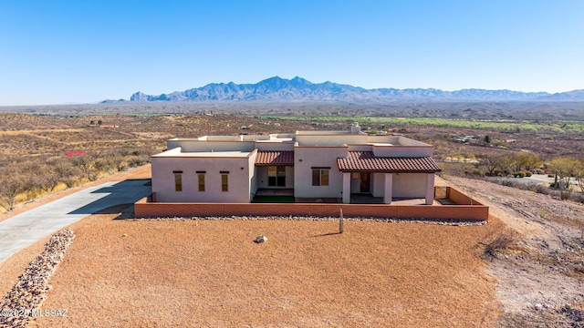 pueblo-style house with a tile roof, a mountain view, and stucco siding