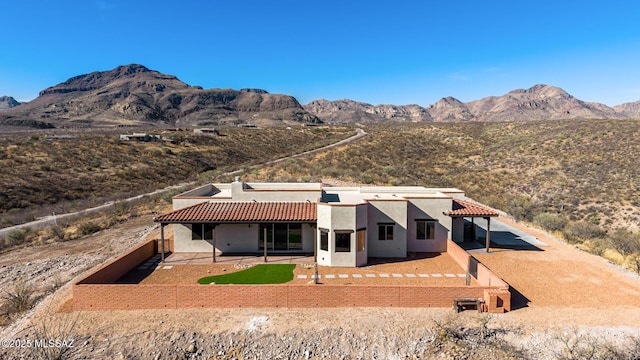 view of front of home with stucco siding, a patio area, fence, a mountain view, and a tiled roof