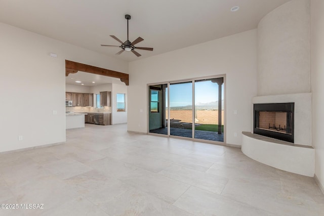 unfurnished living room with baseboards, a fireplace with raised hearth, a ceiling fan, and recessed lighting