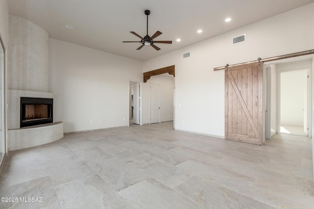 unfurnished living room with a barn door, visible vents, ceiling fan, a fireplace, and recessed lighting