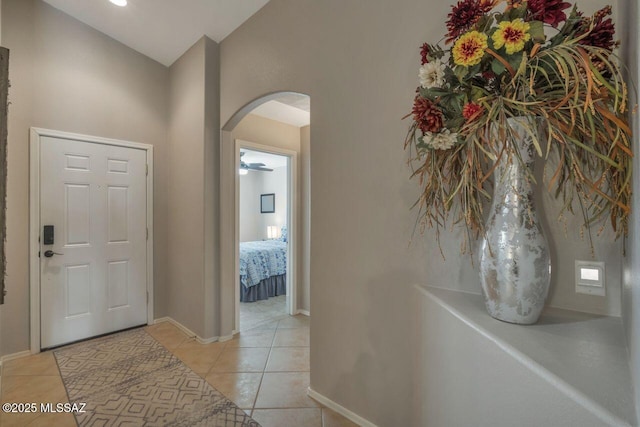 entrance foyer featuring lofted ceiling, light tile patterned floors, baseboards, and arched walkways