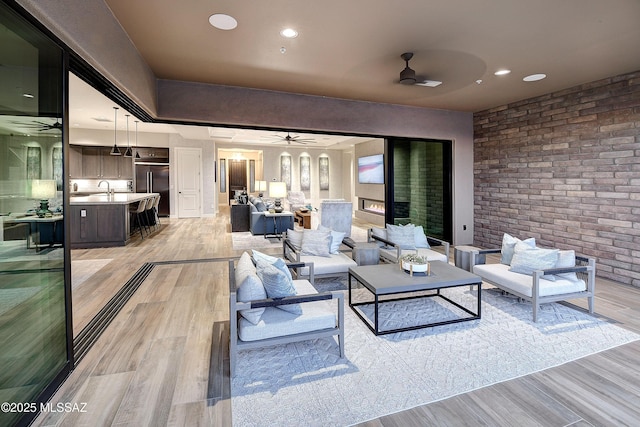 interior space featuring brick wall, light wood-style flooring, ceiling fan, and recessed lighting