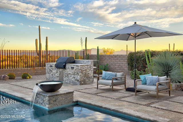 patio terrace at dusk featuring a grill, a fenced backyard, and area for grilling